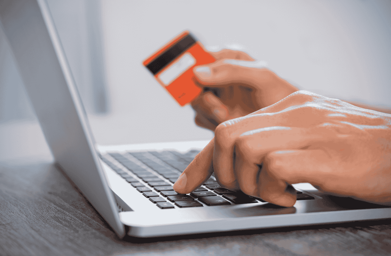 Persona usando tarjeta de crédito para compra online en laptop.
